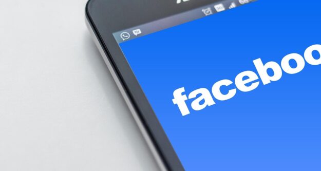 Facebook logo on the mobile screen represents how to rank posts on top of Facebook news feeds.